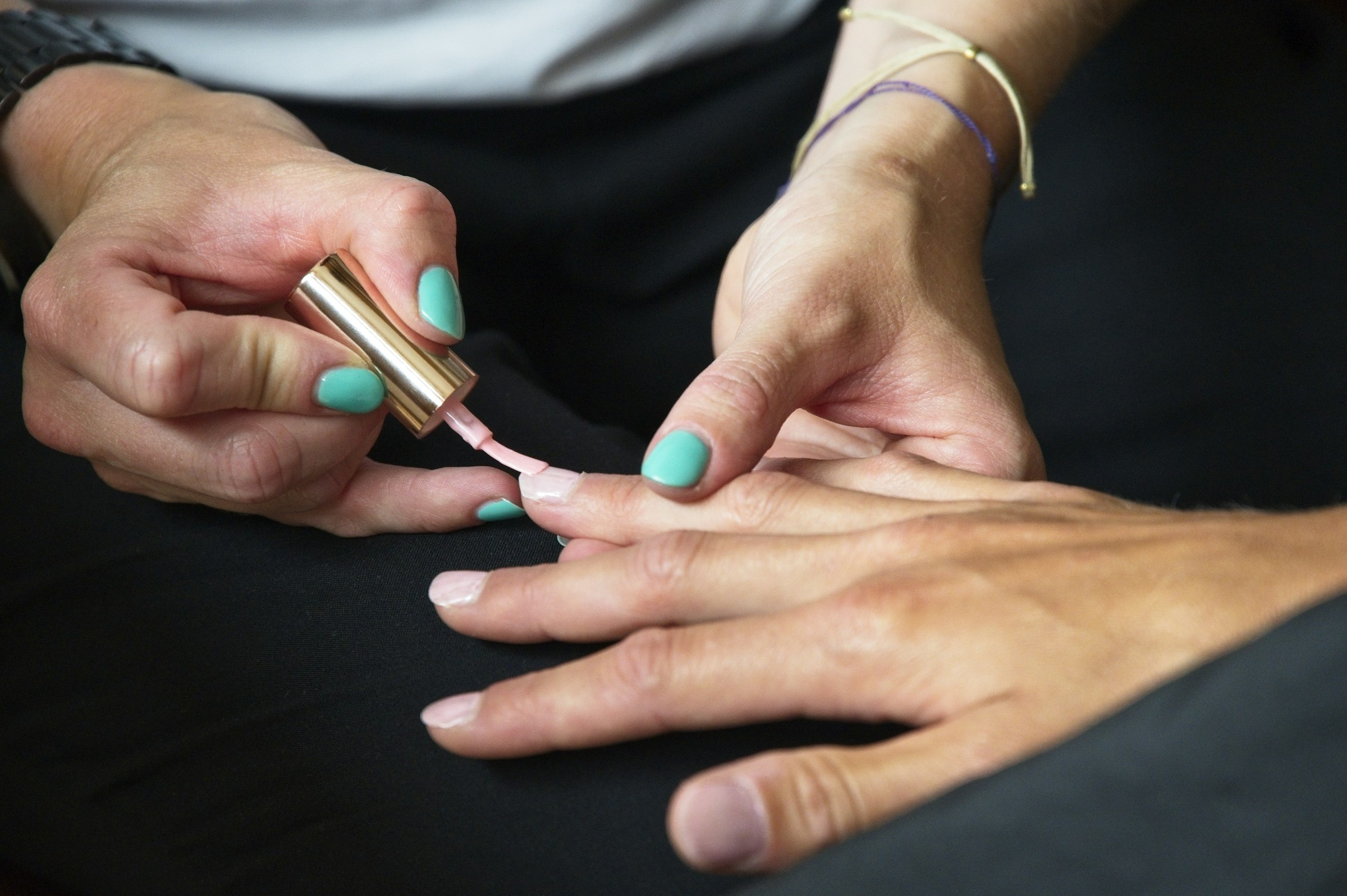 Teal nail polish being applied to fingernails
